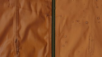 Close-up of waterproof fabric with water droplets beading on the surface.