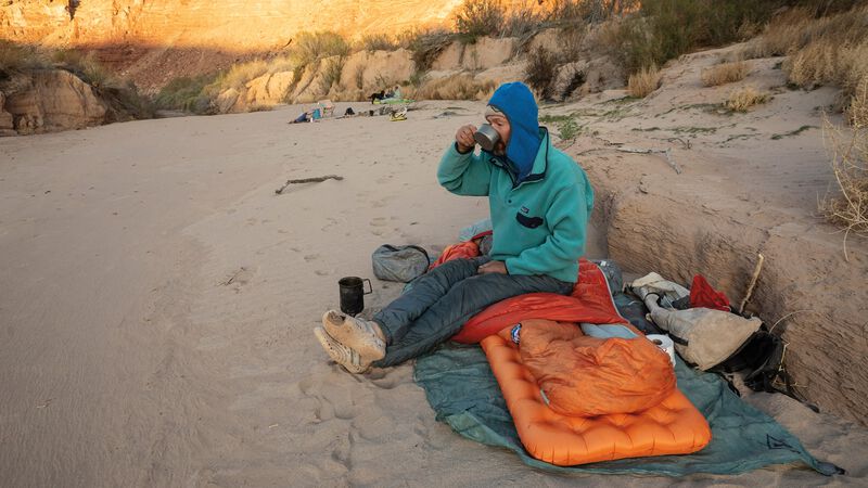 A man drinks from a cup in a dry wash.